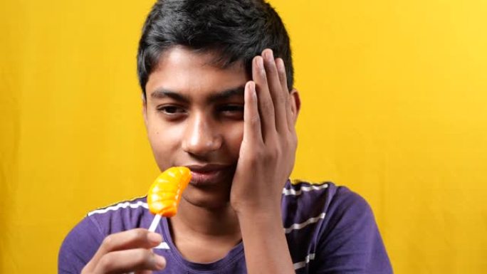 十几岁的男孩在吃棒棒糖时牙齿敏感