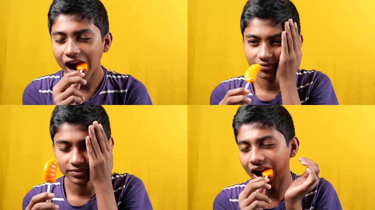十几岁的男孩在吃棒棒糖时牙齿敏感