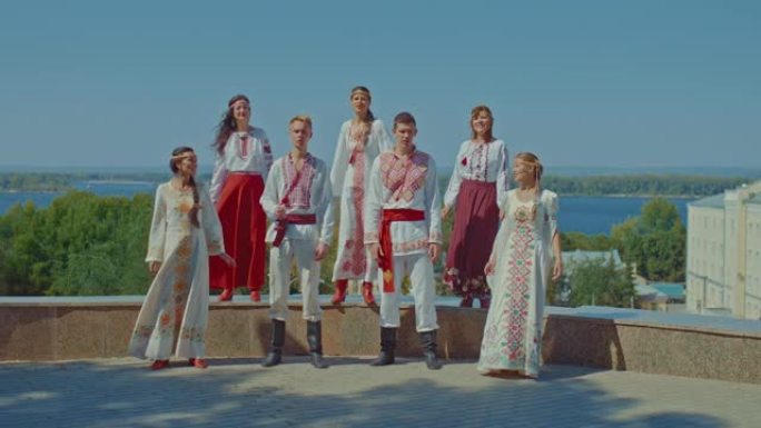 斯拉夫人民站在城市的山丘上唱歌。穿着民族服装带着刺绣的男女欢快地唱着歌，他们是幸福的。人民的友谊。4