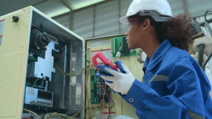 经验丰富的女性电气工程师经过艰苦的工作，正在检查焊接机器人电气控制系统的电气系统，并进行操作测试。