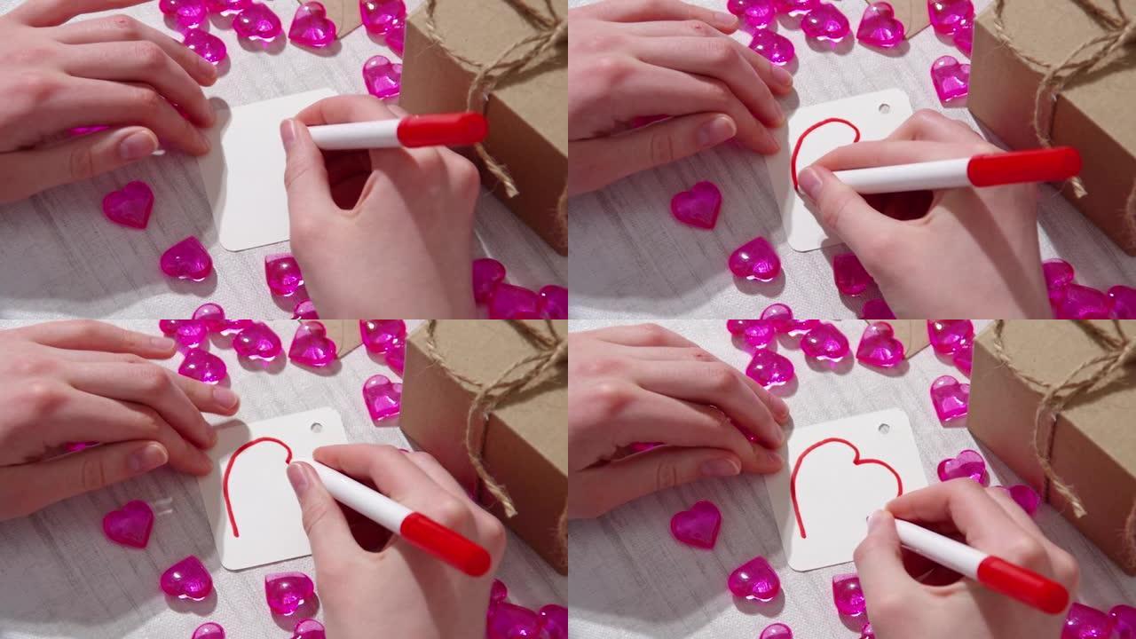 用红色毡尖笔手绘，在一张带有心形和礼物的桌子上的白纸上标记心形。情人节礼物的自制标签。爱与和平的主题