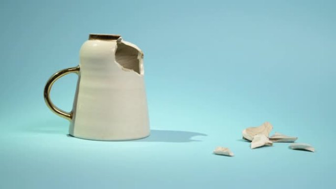 破碎的茶杯孤立在蓝色背景上。破裂的咖啡杯和易碎的陶瓷片
