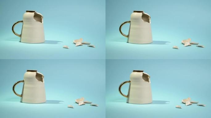 破碎的茶杯孤立在蓝色背景上。破裂的咖啡杯和易碎的陶瓷片