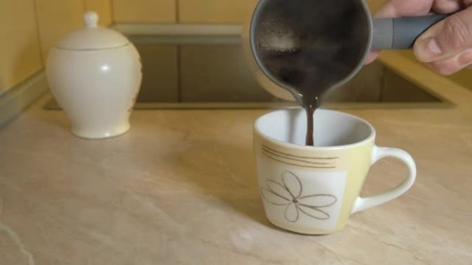 一个人将刚煮好的咖啡从电锅倒入站在厨房柜台上的杯子中，近距离拍摄