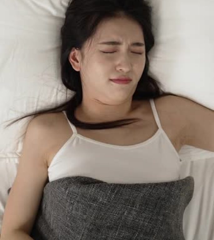 垂直屏幕: 从上方观看睡过头的亚洲日本妇女醒来时发出警报，并以震惊的表情急忙下床，因为她早上在家上班