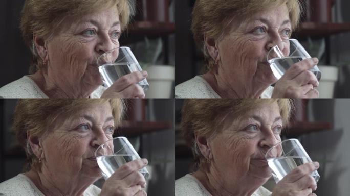 一位老妇从杯子里喝水。恢复体内液体平衡