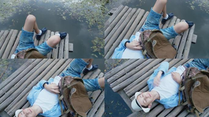十几岁的男孩躺在湖边的码头上，夏天放松，与大自然联系