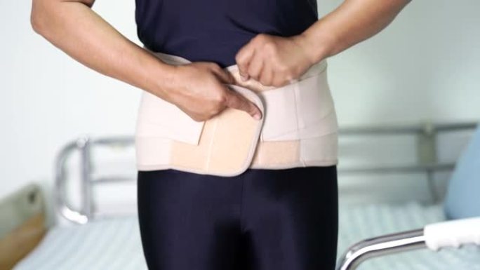 亚洲女性患者穿着背部疼痛支撑带，用于带助行器的骨科腰椎。