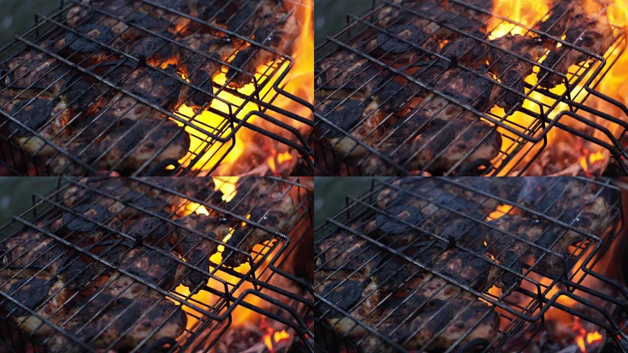 慢动作视频，特写。烤架上的鸡腿。一场美丽的大火在煤上猛烈燃烧。鸡肉在火上过度暴露，有点烧焦了。
