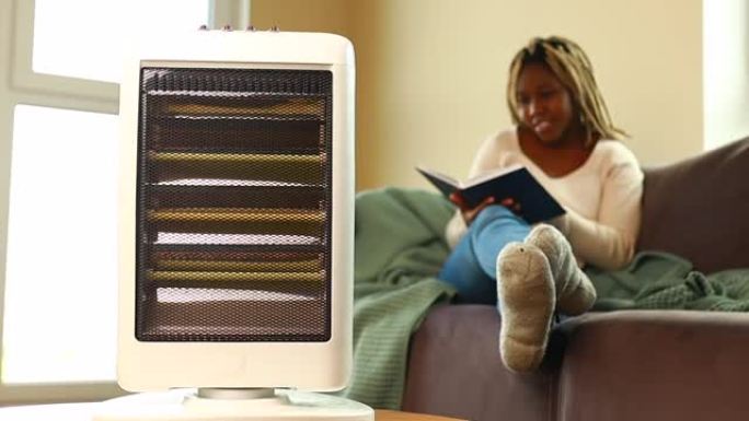 带毯子的拉丁美洲妇女在带加热器的冷藏室里看书