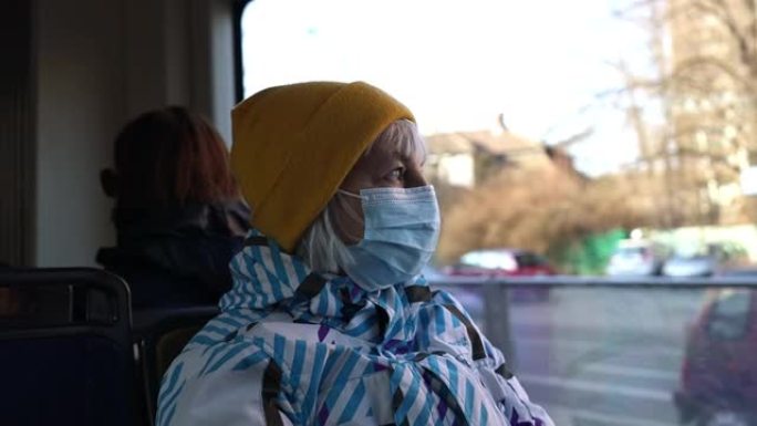 戴着医用口罩的高级妇女坐在公共汽车运输工具上。