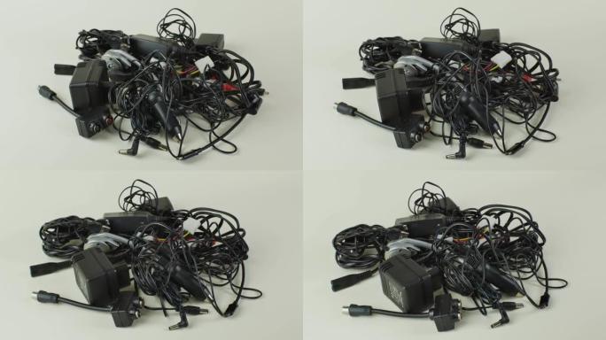 一堆旧电线，连接和充电器的现代设备特写镜头在一个轻的背景。一堆旧电线，连接和充电器，隔离在轻背景上。