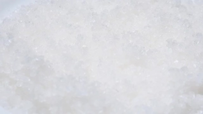 白雪海盐在盘子上旋转的俯视图。水晶盐背景。