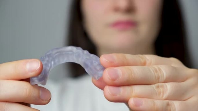 一名妇女显示牙科护齿，夹板用于治疗颞下颌关节功能障碍，磨牙症，错牙合畸形，以放松颌骨的肌肉。