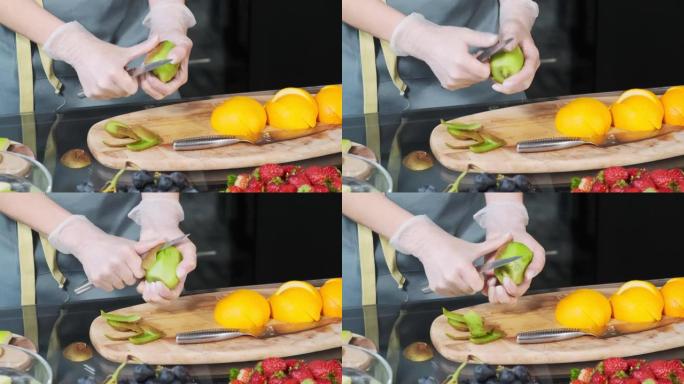 年轻女子在厨房的木板上从果皮上剥下新鲜的猕猴桃。健康食品概念