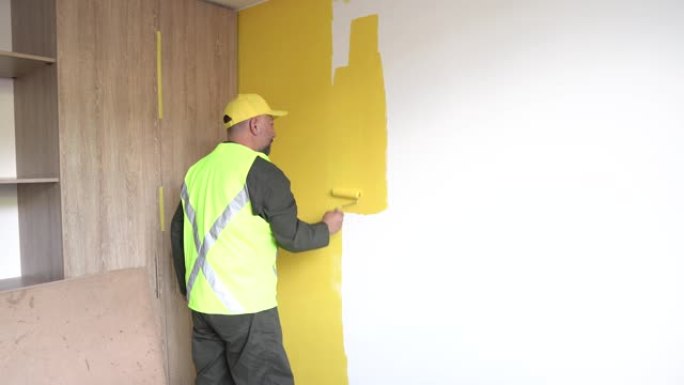 男人穿上制服，将新房子的墙壁涂成黄色