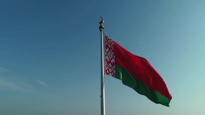 在一个阳光明媚的早晨，白俄罗斯国旗飘扬在蓝天和明斯克的城市景观上