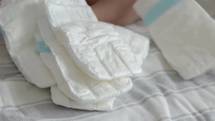 床上尿布中的许多婴儿堆放在床上的女人手数着扔在毯子上