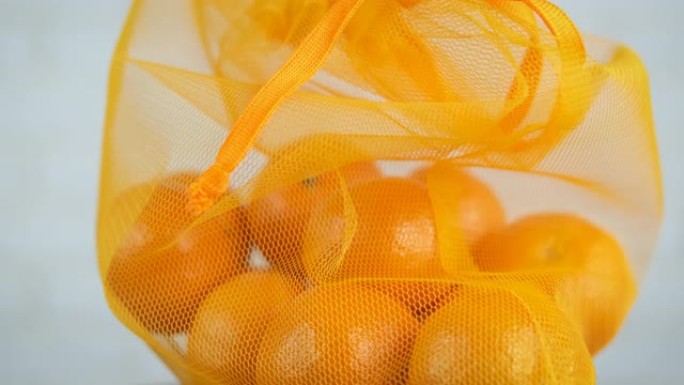 手里拿着橘子的细绳袋。