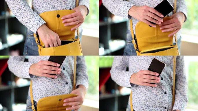 女人的手从黄色皮包中取出智能手机