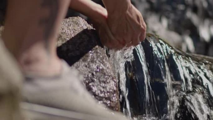 特写:口渴的女人从小溪里舀水洗手