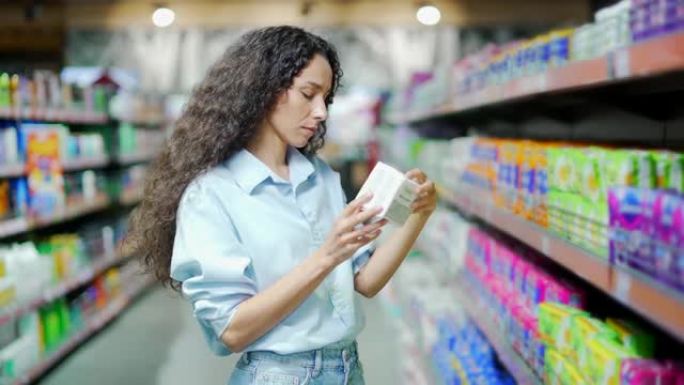 年轻的西班牙裔妇女在超市或商店各种卫生护垫中选择个人护理产品。女性选择家用化学品。