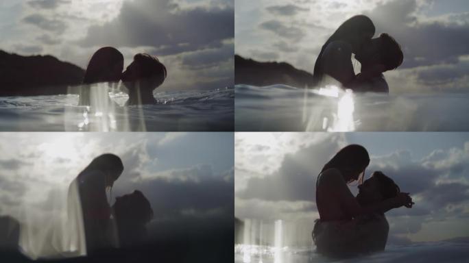 浪漫的异性恋夫妇在日落时一起在海里游泳。在水中接吻和玩耍