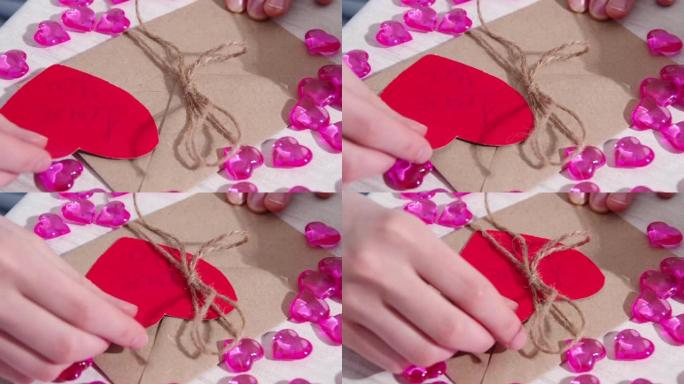女性的手装饰着一个纸信封和一颗红色的心形纸，上面写着我爱你，特写镜头。情人节礼品包装。情人节的问候
