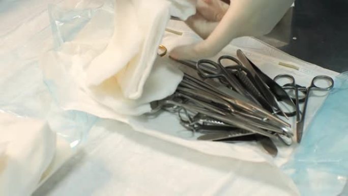 外科医生的助手为手术打开了一套无菌器械。手术器械布置在手术室的金属托盘中。无菌仪器的概念。