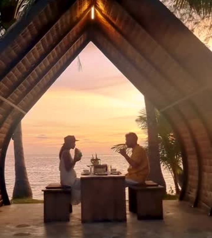 日落时分，一对男女在泰国麦岛的海滩上享用浪漫的晚餐