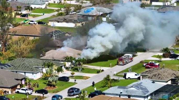 房屋着火的鸟瞰图和消防员在短路导致火花点燃被飓风伊恩风损坏的木质屋顶后扑灭火焰。佛罗里达郊区的家庭灾