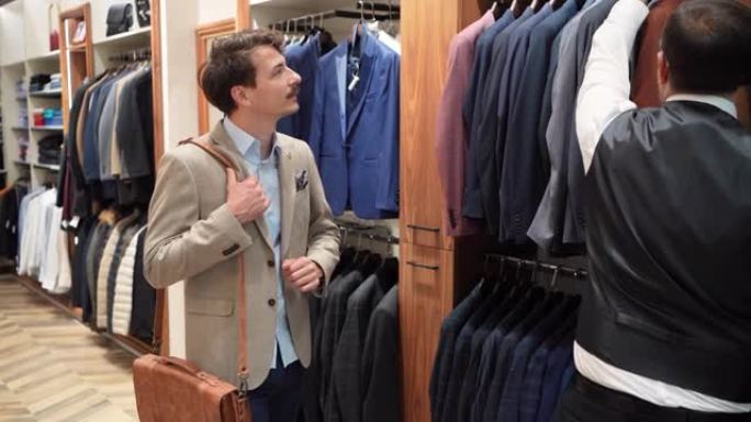 在奢侈品精品店，推销员向男性顾客展示他想尝试的西装