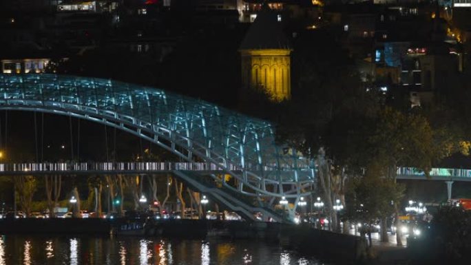 格鲁吉亚第比利斯。晚上的和平之桥街道照明。发光的灯。晚间照明下库拉姆克瓦里河和平桥的夜景