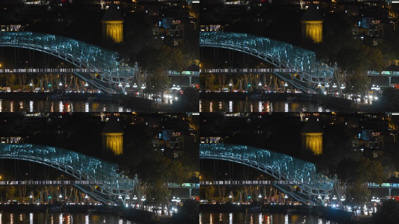 格鲁吉亚第比利斯。晚上的和平之桥街道照明。发光的灯。晚间照明下库拉姆克瓦里河和平桥的夜景