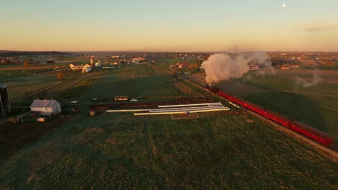 从蒸汽机的上下和后面看无人机，在秋天的早晨，日出时吹着大量烟雾穿过农田