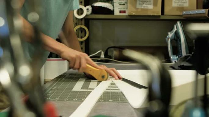 设计，女裁缝师的特写手，通过剪刀和纸板图案草稿裁缝裁切服装样品图案。工业纺织服装厂，制造库存视频