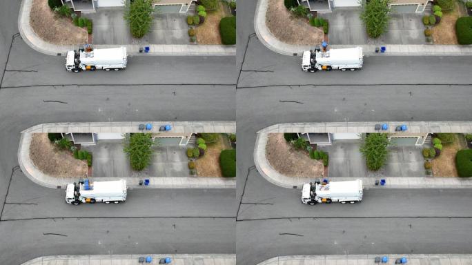 一辆垃圾设施卡车从郊区家庭捡起一堆回收物的鸟瞰图。