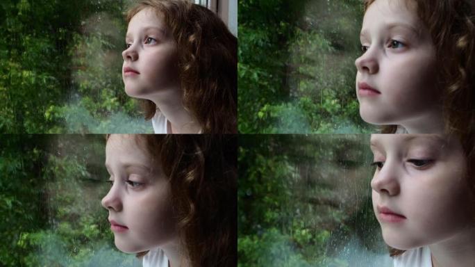 悲伤的小女孩看着窗外的雨滴穿过潮湿的玻璃秋天的恶劣天气。