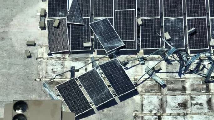 被安装在工业建筑屋顶上的飓风伊恩风破坏的光伏太阳能电池板被破坏，用于产生绿色生态电力。自然灾害的后果