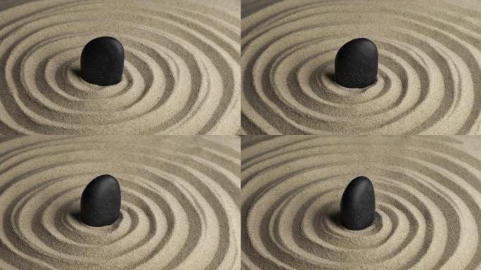 黑石在沙子螺旋中心的旋转。沙子中的图案特写