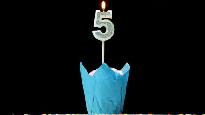 带有5号蜡烛的节日蛋糕在转盘特写镜头上的黑色背景上点燃。周年蛋糕。带有开胃馅饼的生日装饰在桌子上旋转