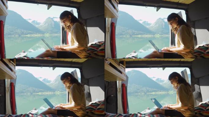在湖边的露营车里用笔记本电脑工作的女人
