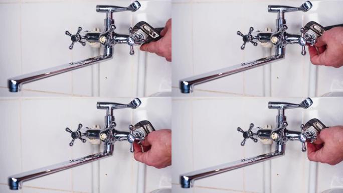 水龙头安装-水管工用可调扳手拧紧螺母。