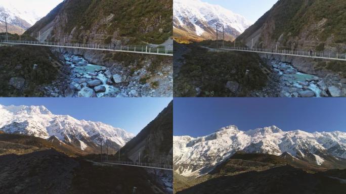 徒步旅行者沿着悬索桥漫步，冲向急流的河水，到达雪山