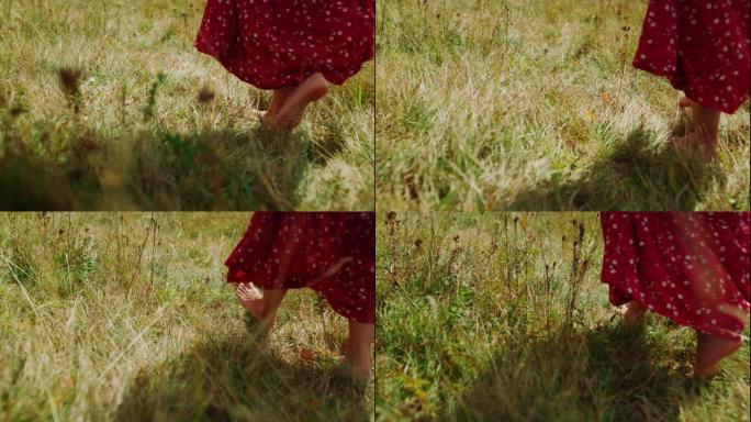 女人的脚踩草特写。默默无闻的女孩独自走在大自然上。