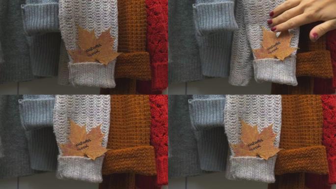 秋季概念。女性手将枫叶与文本秋天的心情放在舒适的保暖毛衣上。针织羊毛和马海毛毛衣。Hygge风格