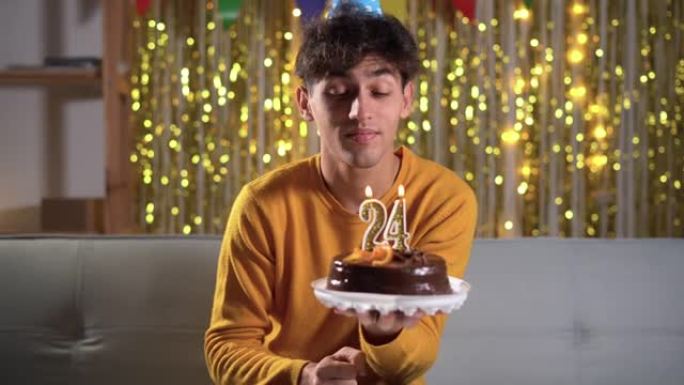 24岁生日。年轻人在生日蛋糕上吹蜡烛二十四。拿着蛋糕的人许愿