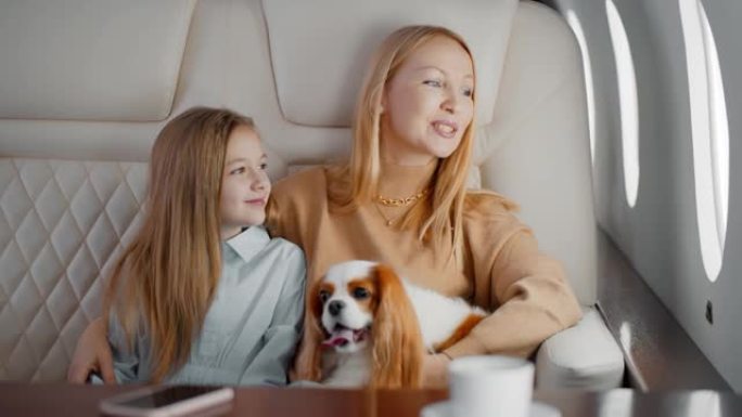 成熟的母亲和未成年的女儿与狗一起乘坐私人飞机旅行
