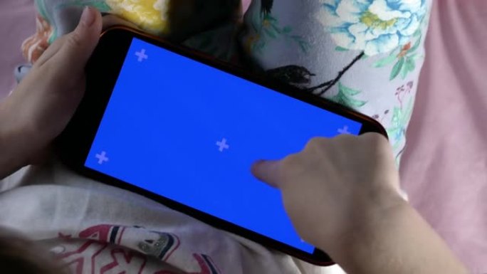 智能手机在儿童手中，显示屏背光并带有蓝色指示。