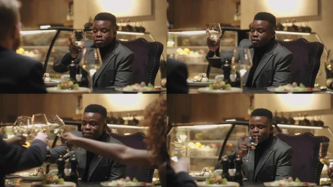 非洲男子在餐厅的朋友或家庭聚会上敬酒，多民族庆祝